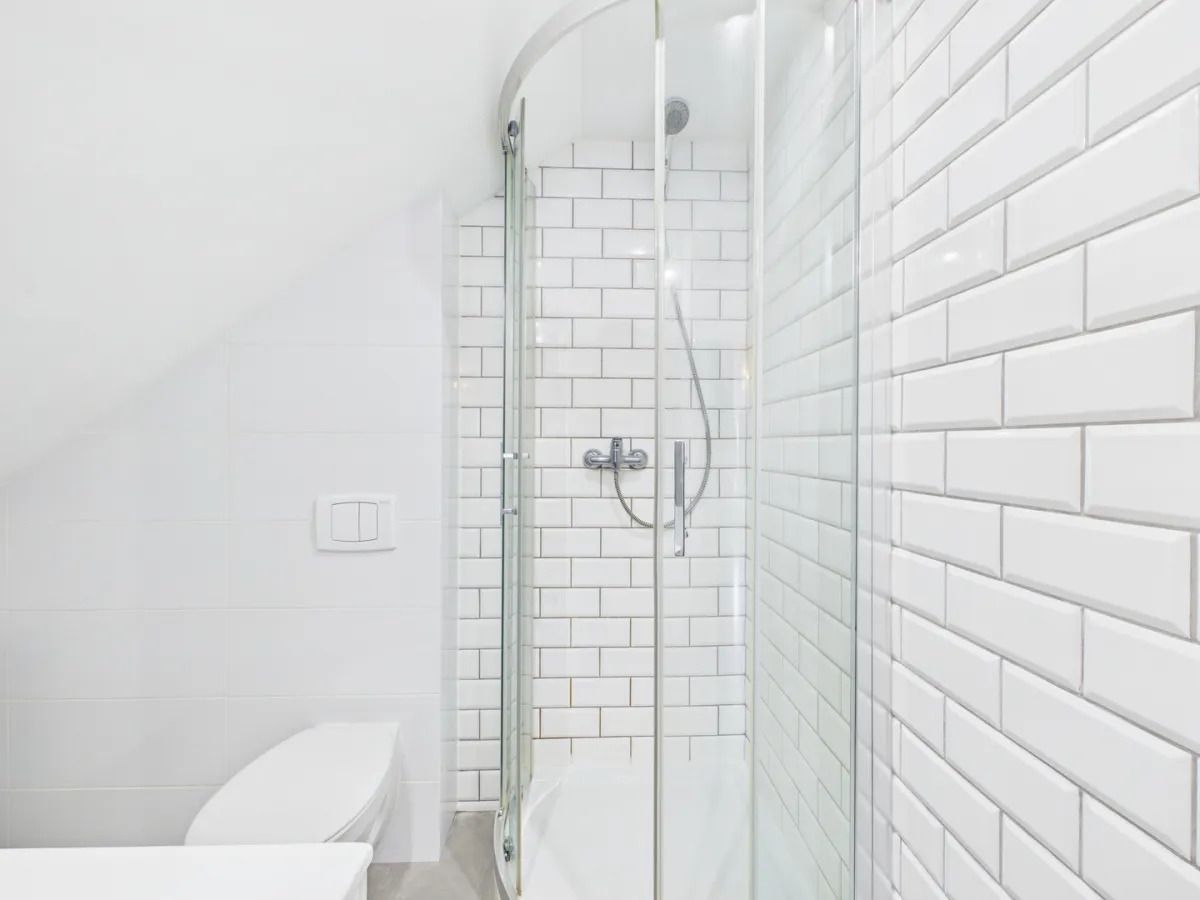 Une salle de bain moderne avec des carreaux de métro blancs, une douche en verre et des toilettes blanches.