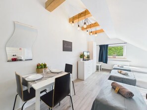 A modern room with a dining area, a TV, and a relaxation area with towels. - Super Apart Obywatelska (Warsaw)