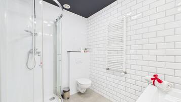 Un bagno moderno con cabina doccia in vetro, un water e un lavabo con un asciugamano.