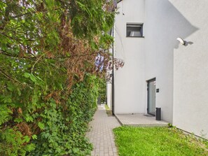 A narrow pathway leading to a white building with a door and a window. - Super Apart Obywatelska (Warsaw)