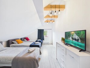 A modern bedroom with two beds, a TV, and a window with curtains. - Super Apart Obywatelska (Warsaw)