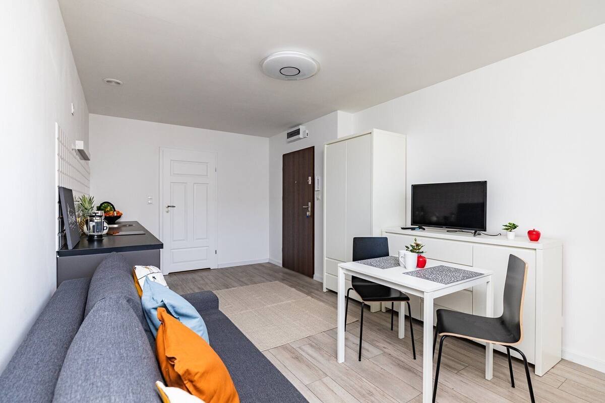 Un apartamento moderno con sala de estar, kitchenette, comedor y televisor.