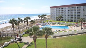 A hotel with a pool, beach view, and palm trees.