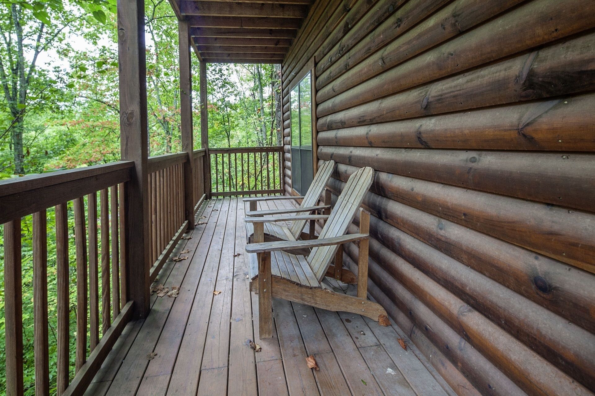 A wooden deck with a bench and a table, surrounded by a wooden railing.
