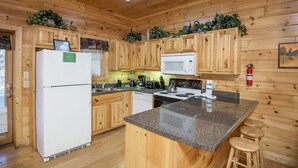 A wooden cabin kitchen with a refrigerator, stove, microwave, and wooden cabinets. - Er 226 - Locker's Mountain Hideaway Great Location - Close To Town! 2 Bedroom Cabin by RedAwning (Pigeon Forge)