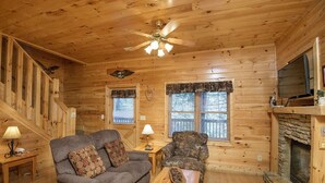 A cozy cabin interior with a wooden ceiling, a fireplace, a couch, a chair, and a table. - Er 226 - Locker's Mountain Hideaway Great Location - Close To Town! 2 Bedroom Cabin by RedAwning (Pigeon Forge)