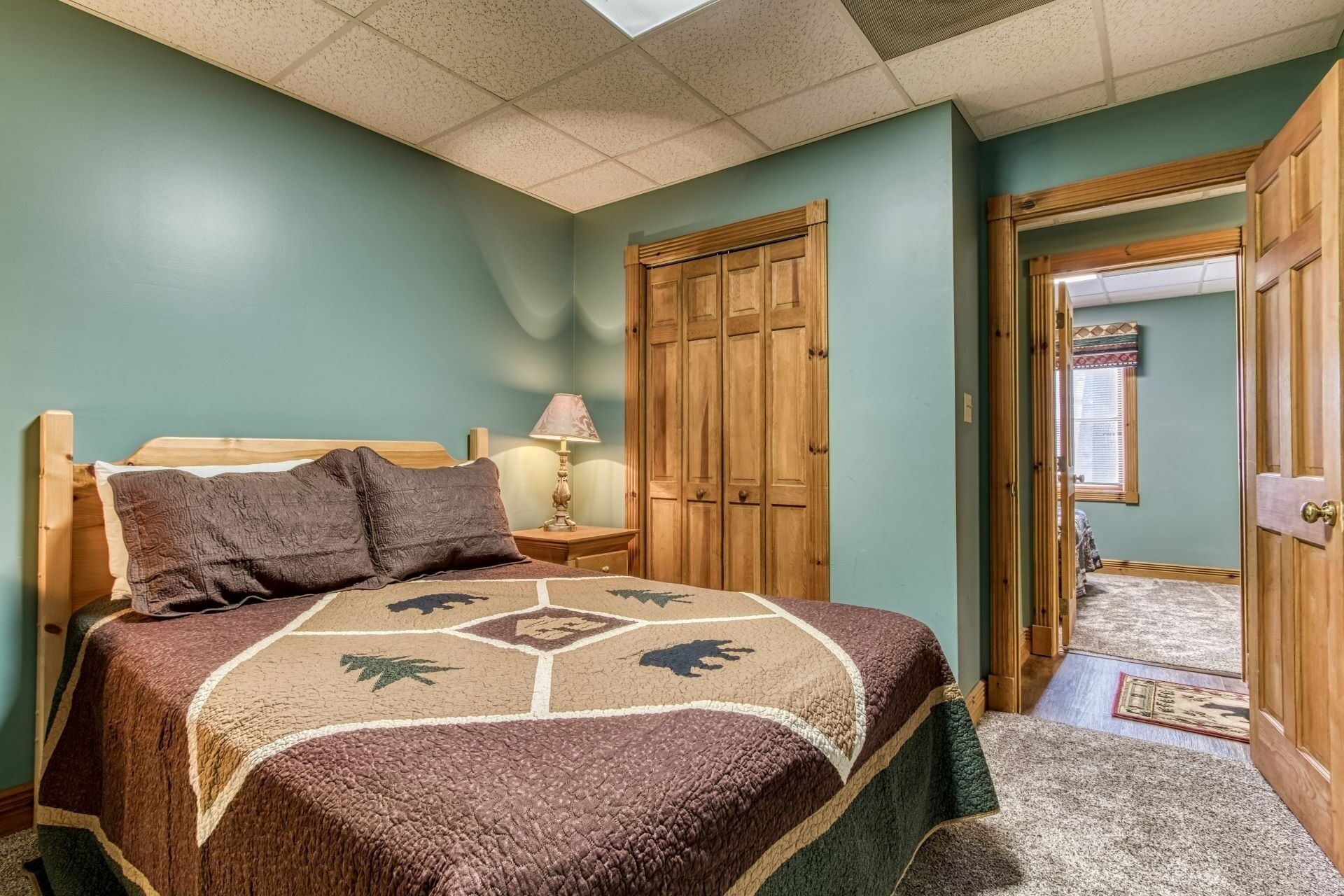 Un dormitorio con cama, armario de madera y mesita de noche con lámpara.