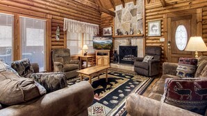 Ein Blockhaus-Interieur mit Kamin, Holzwänden und einer gemütlichen Sitzecke mit Teppich.