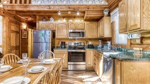 Eine holzhausartige Küche mit Essbereich, ausgestattet mit Kühlschrank, Herd, Mikrowelle und Holzschränken.