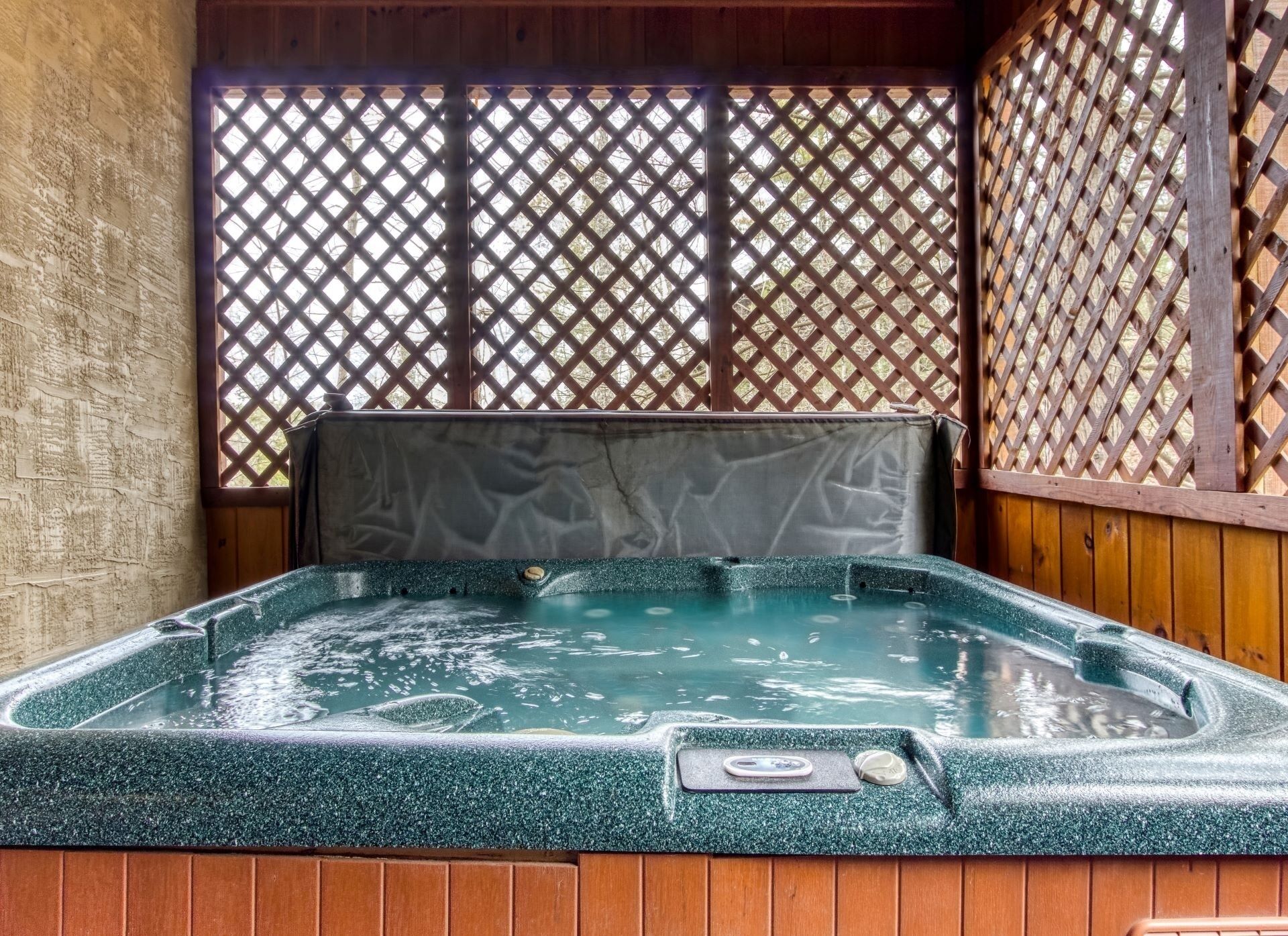 A hot tub with a wooden frame and a lattice backdrop.