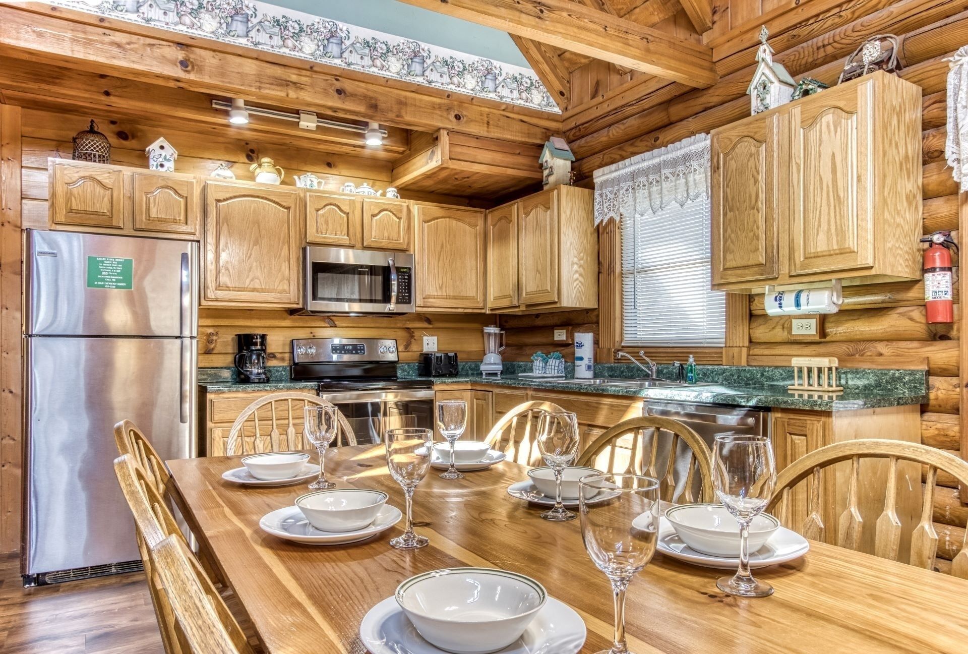 A wooden cabin kitchen with a dining table set for six, a refrigerator, a microwave, and a stove.