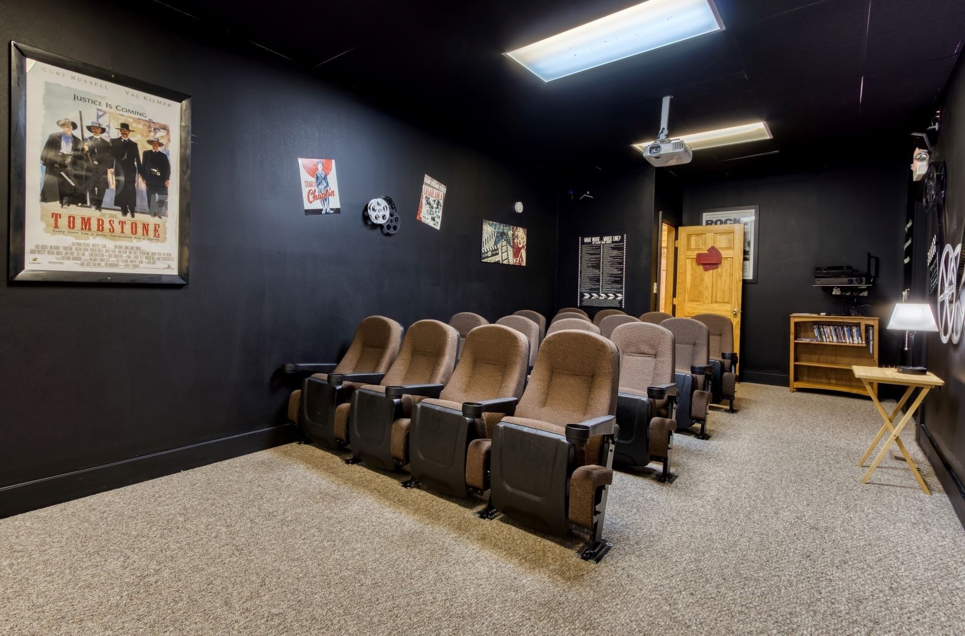 Une salle de cinéma avec des rangées de sièges marron, un projecteur et un écran.