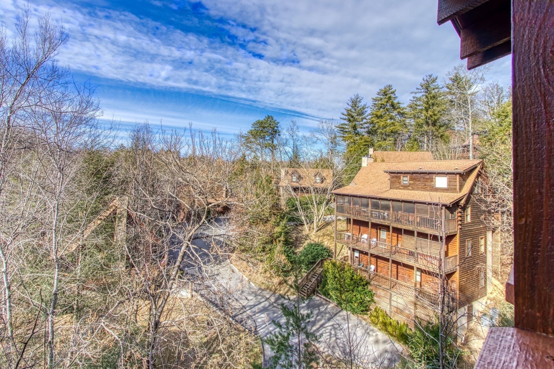 A log cabin with a balcony and a view of a forested area.