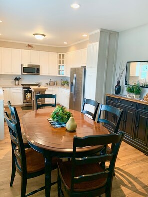 Enjoy meals in the kitchen with a round dining table and six chairs, accompanied by a refrigerator and microwave.