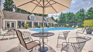 Un jardin avec une piscine, du mobilier d’extérieur et un grand parasol.