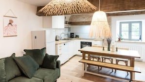 Una cocina moderna con armarios blancos, una mesa de comedor de madera y un sofá verde.