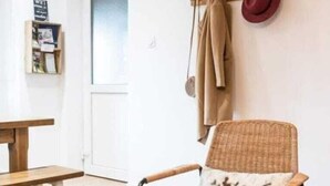 Una habitación acogedora con una mesa de madera, una silla de mimbre y un sombrero colgado.
