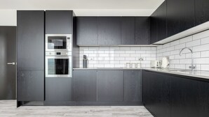 A modern kitchen with dark cabinetry, a stainless steel oven, and a white tiled backsplash.