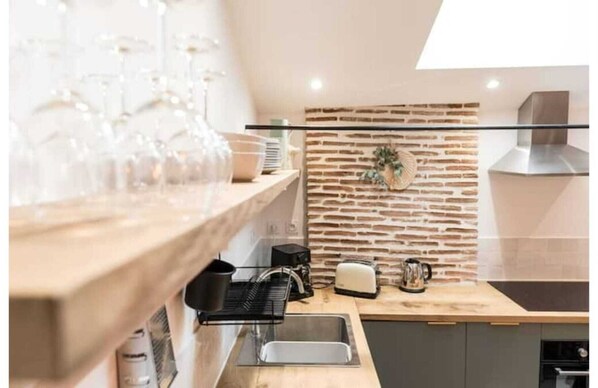 Eine moderne Küche mit einer Wandverkleidung aus Ziegelsteinen, einer Arbeitsplatte aus Holz, einer Spüle und verschiedenen Küchengeräten.