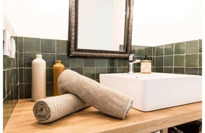 Ein Badezimmer mit einem weißen Waschbecken, einem Spiegel und einem Handtuch auf der Ablagefläche.