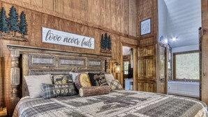 Un dormitorio rústico con cabecera de madera, colcha acolchada y un cartel que dice 'love never fails'.