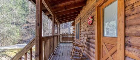 A wooden cabin with a porch, a rocking chair, and a decorative wreath.