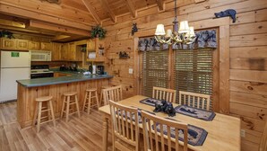 A wooden cabin interior with a dining area, kitchen, and bar. - Er302 - Best Of Times Great Location-close To Town 2 Bedroom Cabin by RedAwning (Pigeon Forge)
