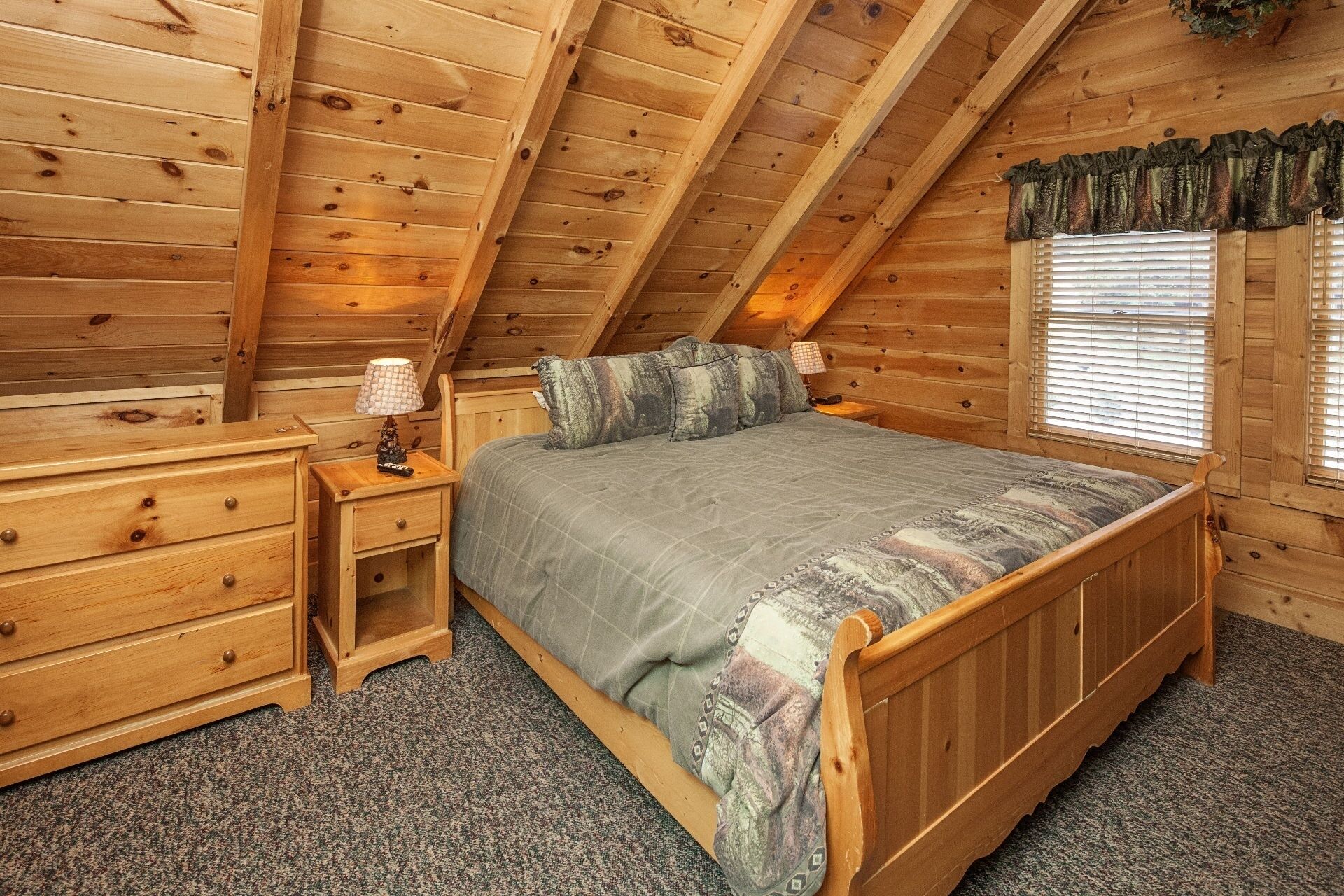 A cozy attic bedroom with a wooden bed, nightstands, and a dresser.