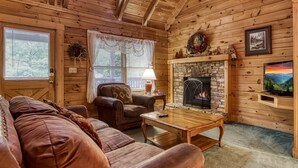A cozy cabin interior with a stone fireplace, leather furniture, and a television. - Er2 - Heavenly View Great Location! - Close To Town! 2 Bedroom Cabin by RedAwning (Pigeon Forge)
