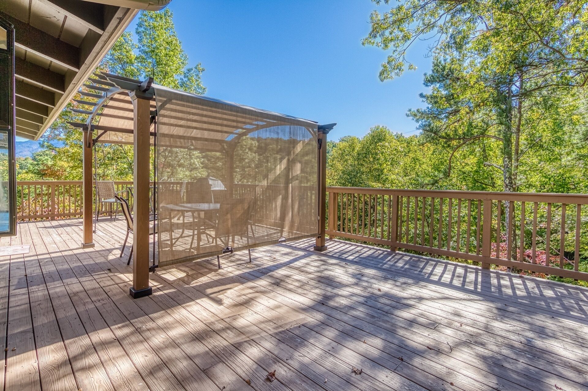 A wooden deck with a covered seating area, a table, and chairs.