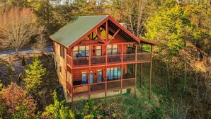 A cabin with a balcony, surrounded by trees and water. - Ern858 - Eagles On High - Great Location! Close To All The Action! 3 Bedroom Cabin by RedAwning (Pigeon Forge)
