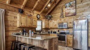 A kitchen with wooden cabinets, a stainless steel refrigerator, a granite countertop, and a clock on the wall. - Ern858 - Eagles On High - Great Location! Close To All The Action! 3 Bedroom Cabin by RedAwning (Pigeon Forge)