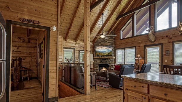 A log cabin interior with a stone fireplace, wooden flooring, and a large TV mounted above it. - Ern858 - Eagles On High - Great Location! Close To All The Action! 3 Bedroom Cabin by RedAwning (Pigeon Forge)