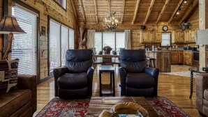 A spacious living room with leather chairs, a dining table, and a chandelier. - Ern858 - Eagles On High - Great Location! Close To All The Action! 3 Bedroom Cabin by RedAwning (Pigeon Forge)