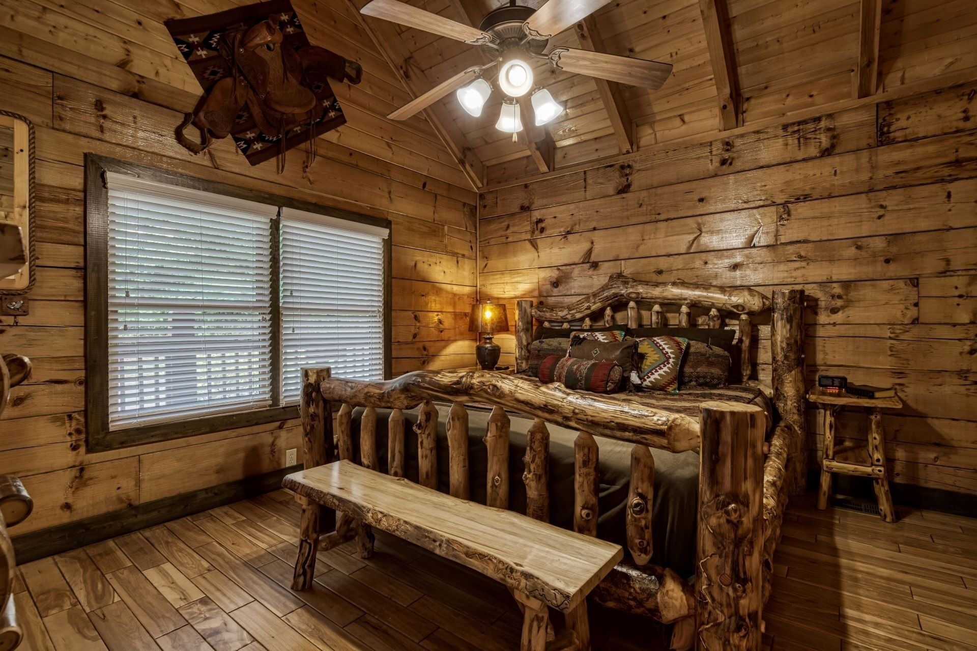 Una habitación rústica de madera con una cama, un banco y un ventilador de techo.