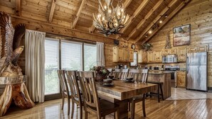 A rustic wooden interior with a dining area, kitchen, and a large wooden sculpture. - Ern858 - Eagles On High - Great Location! Close To All The Action! 3 Bedroom Cabin by RedAwning (Pigeon Forge)