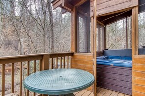 A wooden deck with a glass table and a hot tub. - Er45 - Tin Pan Alley - Great Location. Just Across From Swimming Pool! 2 Bedroom Cabin by RedAwning (Pigeon Forge)