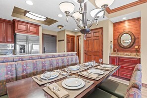 A spacious kitchen with a long dining table set for six, wooden cabinets, a built-in oven, and a large mirror above the sink. - 3701a Westgate 1 Bedroom Condo by RedAwning (Park City)
