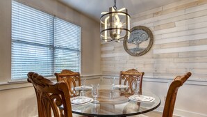 A dining room with a round glass table, wooden chairs, and a chandelier. - Owl See You 3205 - Close To Dollywood And Overlooking Gatlinburg Golf Course 2 Bedroom Condo by RedAwning (Pigeon Forge)
