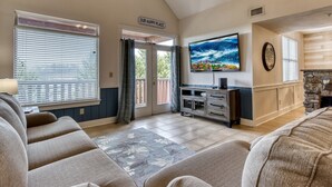 A living room with a TV, a fireplace, and a sign that reads "OUR HAPPY PLACE". - Owl See You 3205 - Close To Dollywood And Overlooking Gatlinburg Golf Course 2 Bedroom Condo by RedAwning (Pigeon Forge)