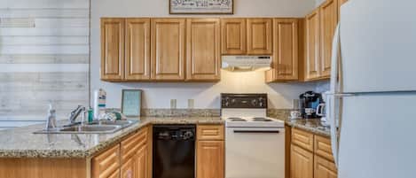 A kitchen with wooden cabinets, a stove, a dishwasher, and a refrigerator.