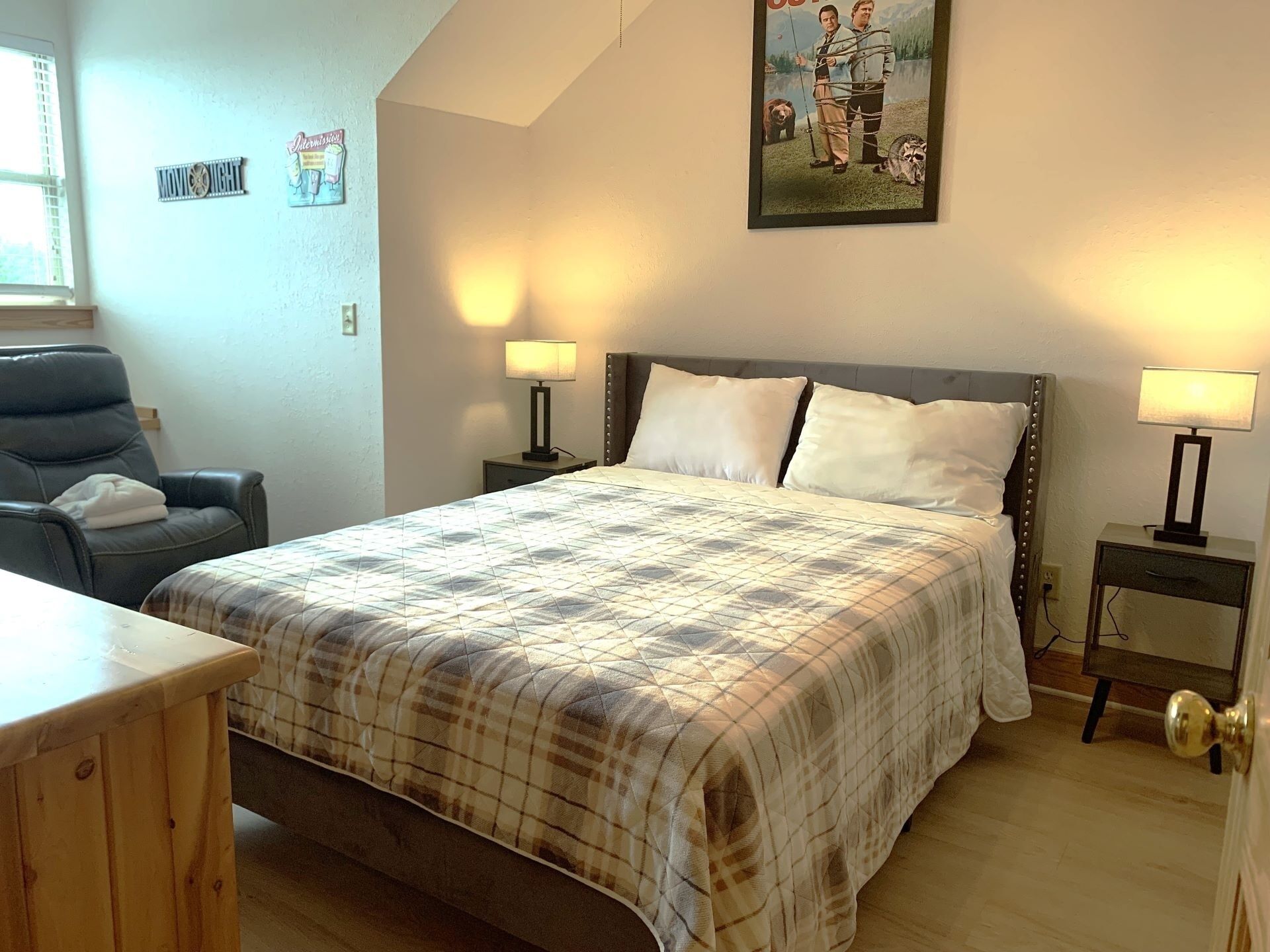 Ein Schlafzimmer mit einem Bett, zwei Nachttischen, einem Sessel und einem Holztisch.