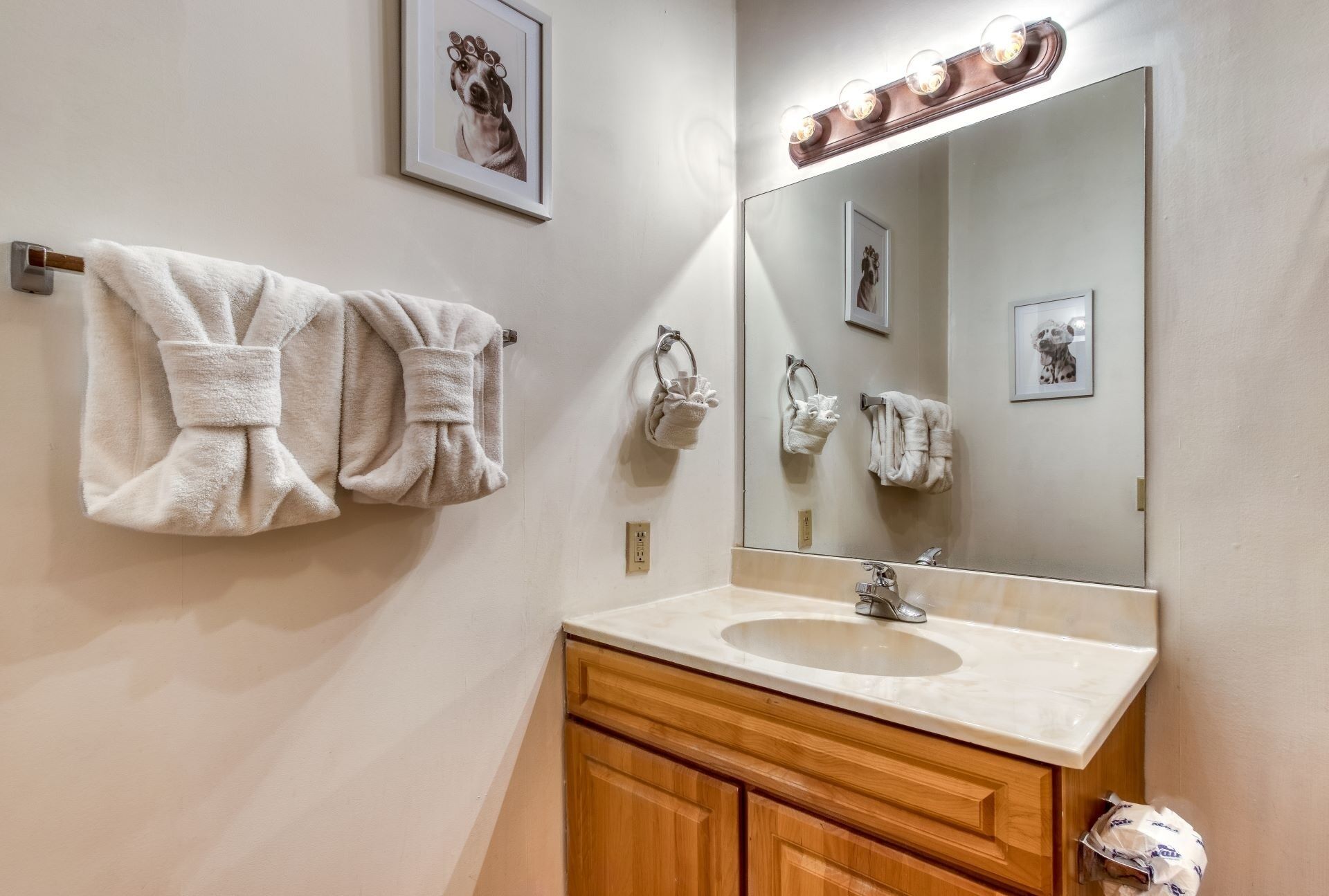 A bathroom with a large mirror, a sink, and two towels hanging on the wall.