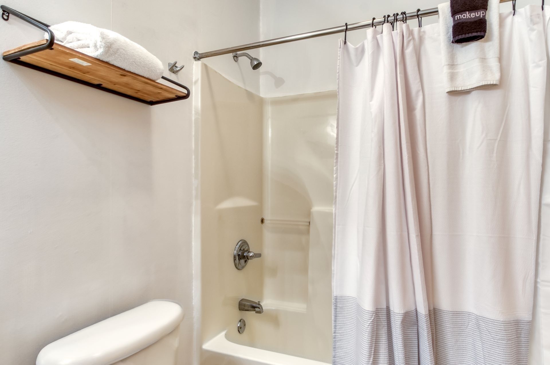 A bathroom with a shower curtain, a towel rack with a towel, and a toilet.