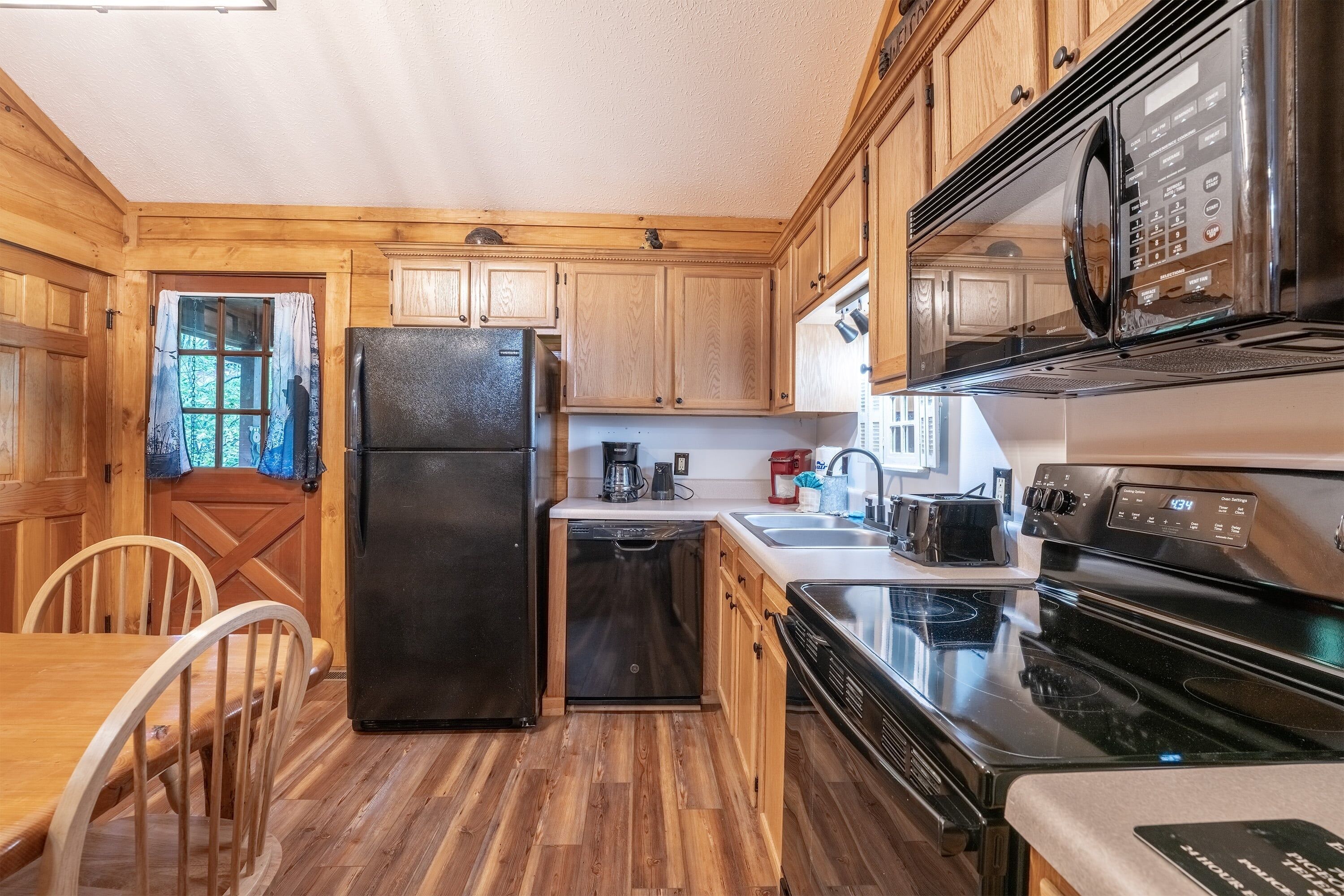 A kitchen with wooden cabinets, a black refrigerator, a dishwasher, a stove, and a microwave.