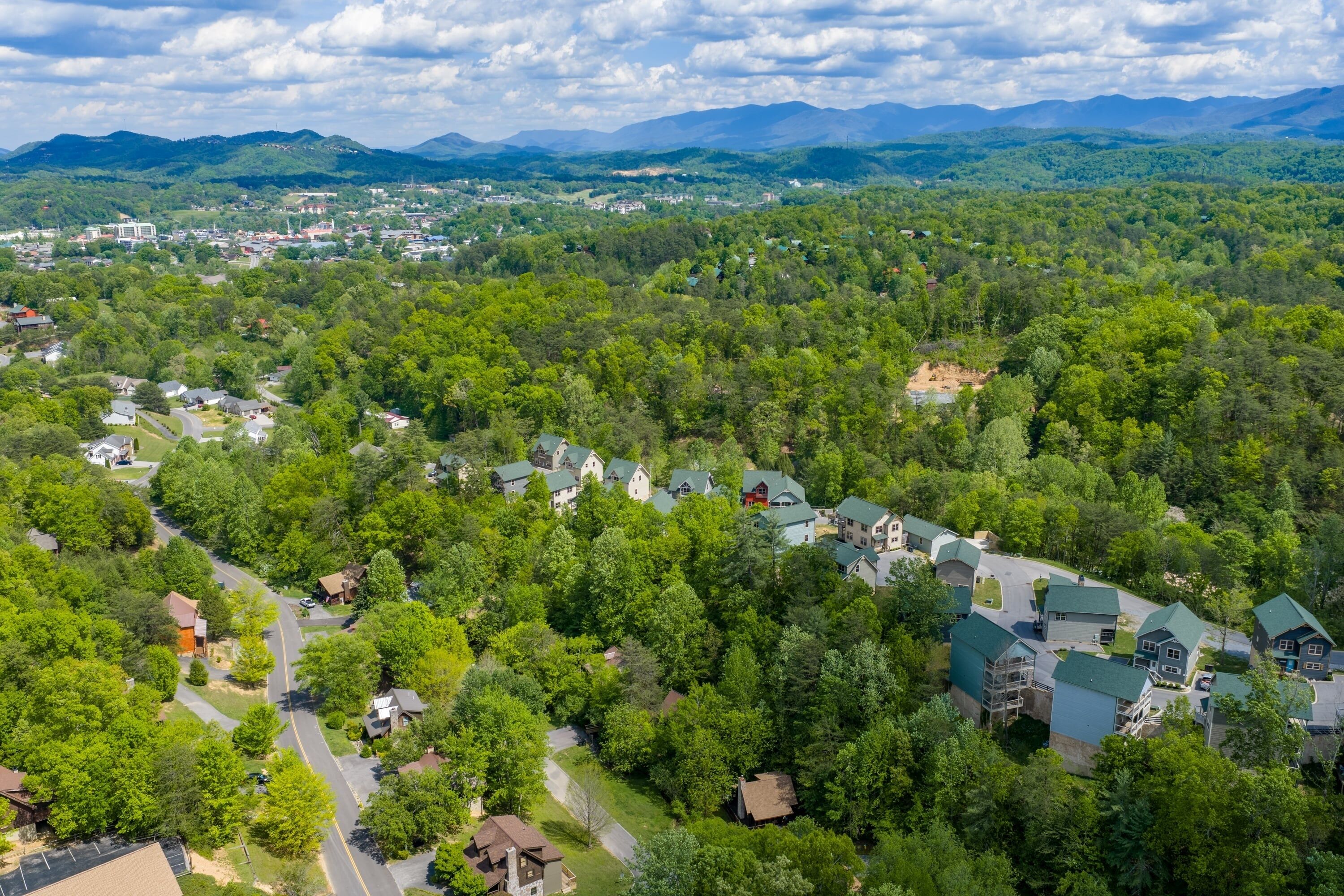 Vue aérienne d’un quartier résidentiel avec des maisons, des routes et la végétation environnante.