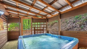 A hot tub in a wooden cabin with a metal roof and wooden walls.