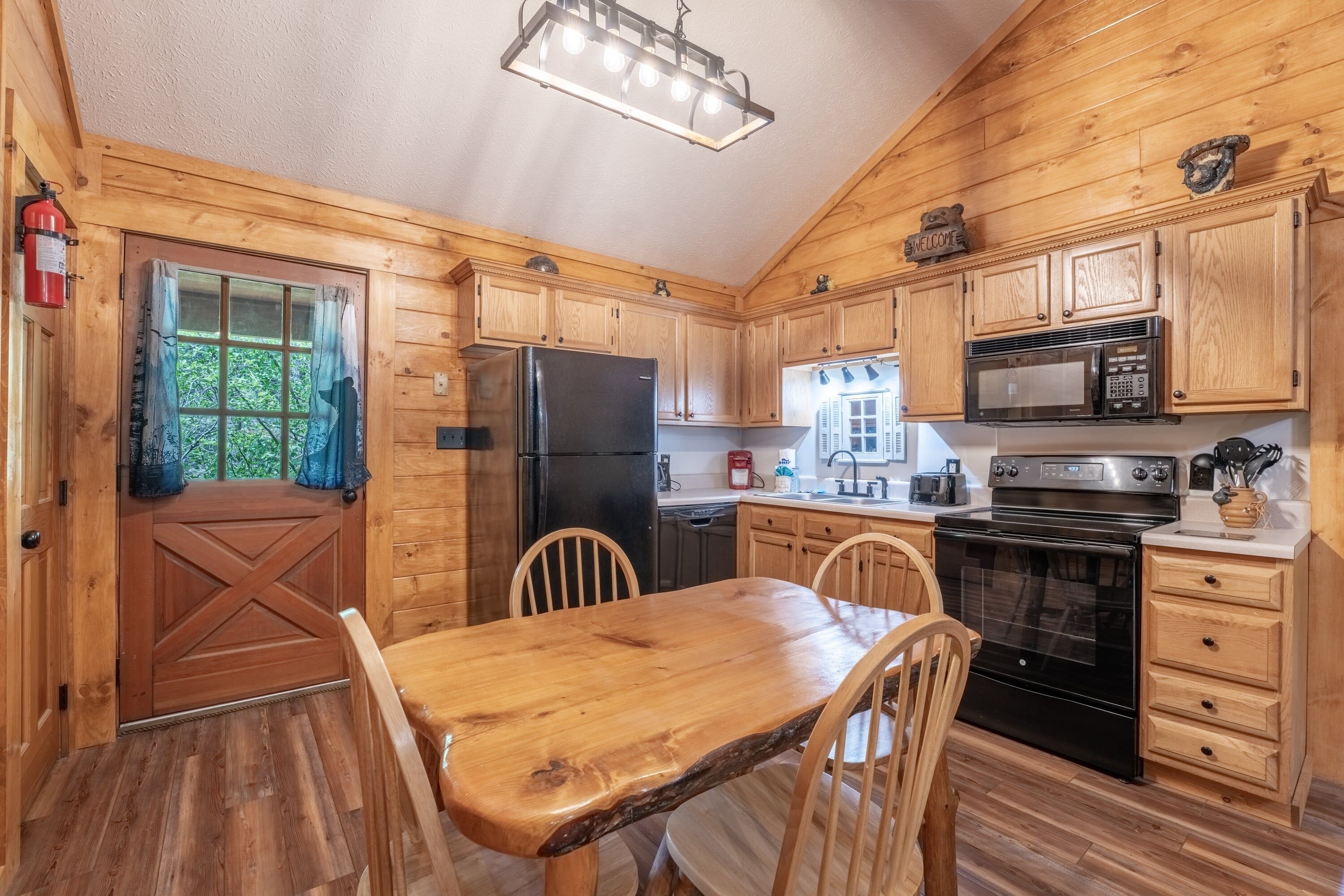 Une cuisine aménagée dans le style d’un chalet en bois, avec une table à manger, des chaises, un réfrigérateur, une cuisinière et un four à micro-ondes.
