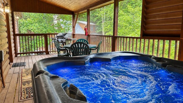 A hot tub on a wooden deck with a view of greenery. - Er31 - Grandma And Granpaws Place - Great Location - Close To Parkway In Pf 2 Bedroom Cabin by RedAwning (Pigeon Forge)
