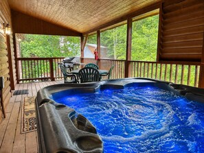 Un jacuzzi en una terraza de madera con vistas a zonas verdes.